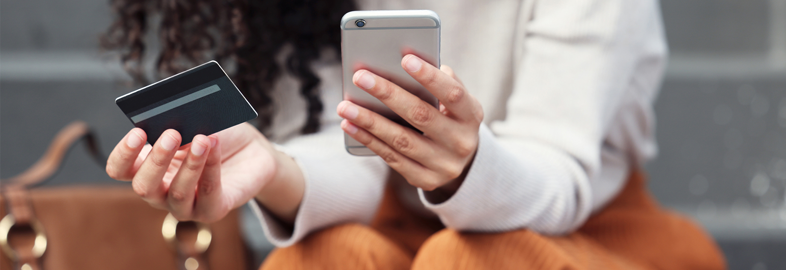 person sitting down holding phone and debit card