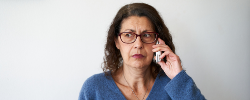 Woman in blue sweater looking concerned while on the phone.