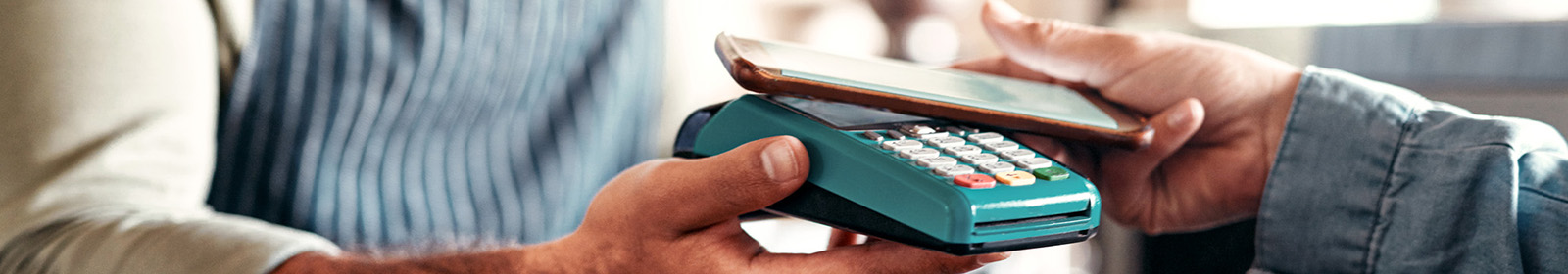 person holding smartphone over payment terminal to make a mobile payment