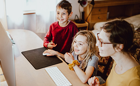 two kids and mom looking at computer smiling