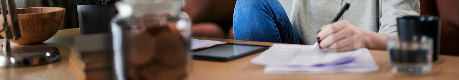 person at coffee table with pen and paper