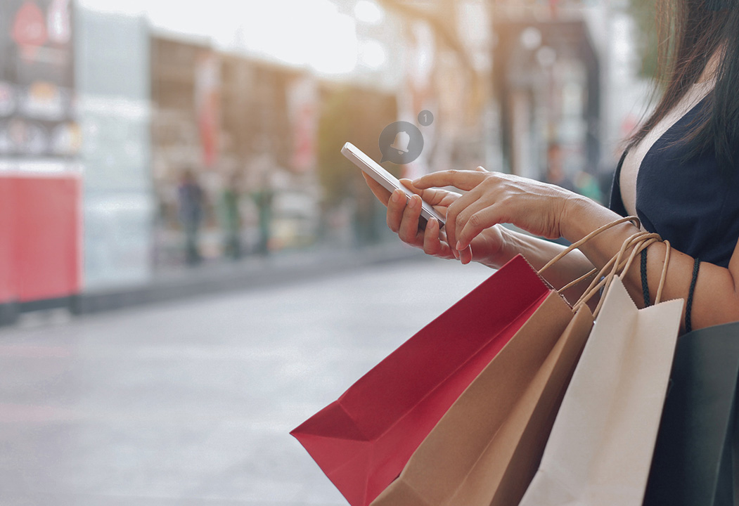 Person holding shopping bags and smartphone