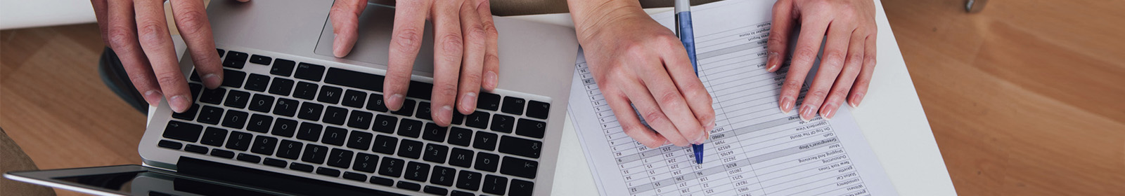 two sets of hands, one set on laptop, one set on piece of paper