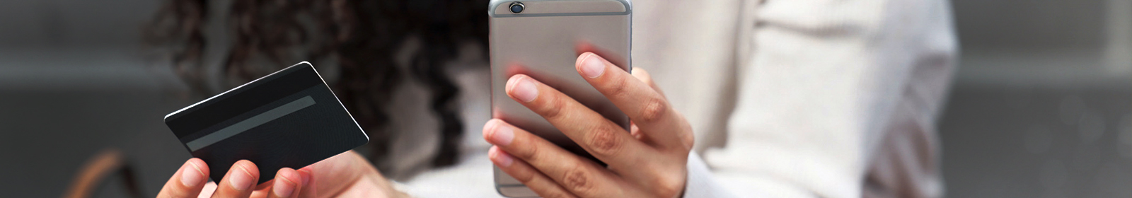 person holding credit card in one hand and phone in the other