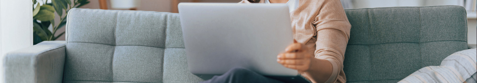 person on couch with open laptop