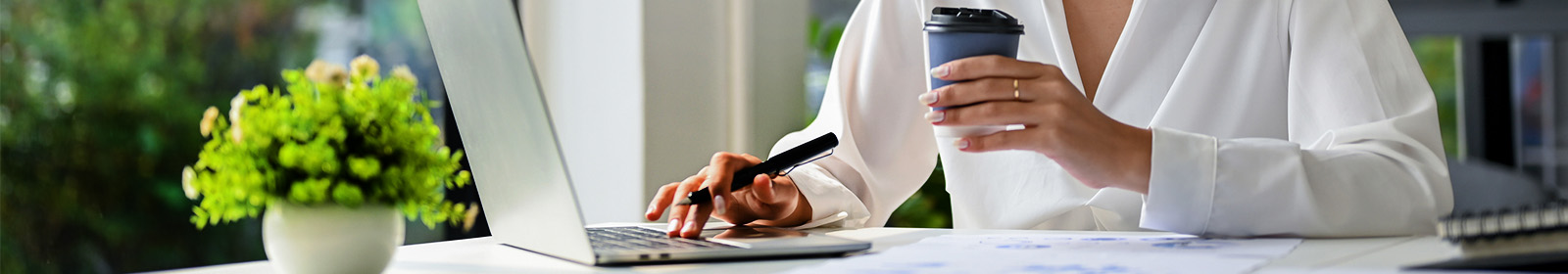 zoomed in image of woman at computer holding coffee cup